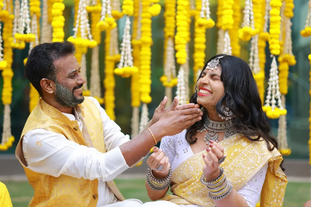 Joyful haldi ceremony moment where groom applies turmeric to the smiling bride, captured by Chikkarams Cinematic Wedding Photography in Hyderabad
