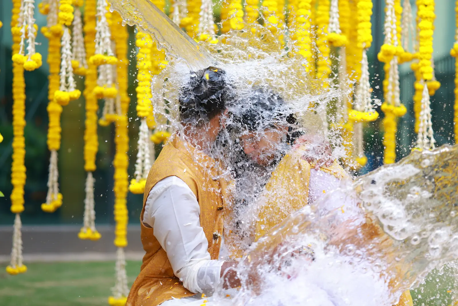 Fun haldi ceremony water splash between the couple captured by Chikkarams Wedding Photography in Hyderabad, showing joyful celebration and candid emotion